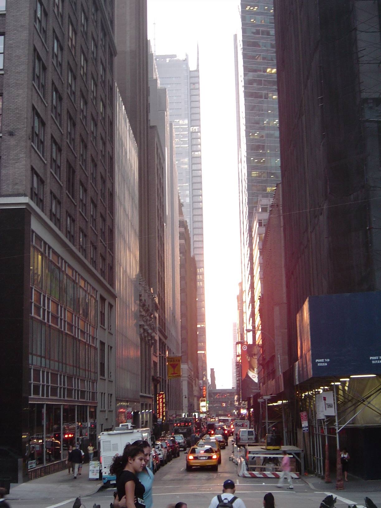 Manhattan skyscrapers in morning light, yellow taxis and pedestrians in the street