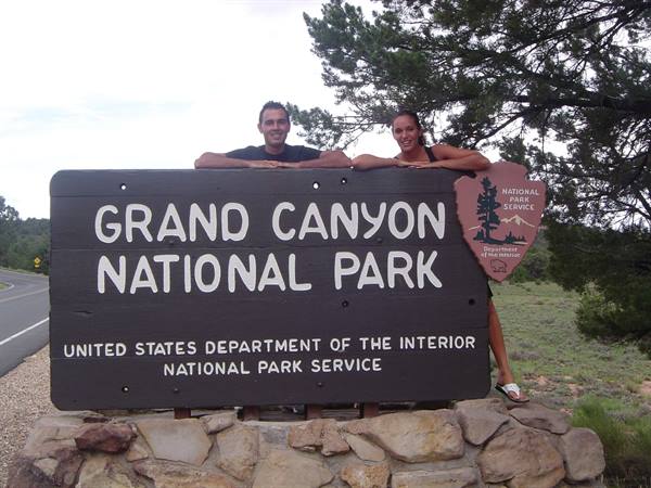 Couple leaning on the wooden Grand Canyon National Park entrance sign