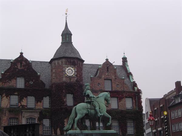 Bronze equestrian statue in front of Düsseldorf City Hall under gray sky