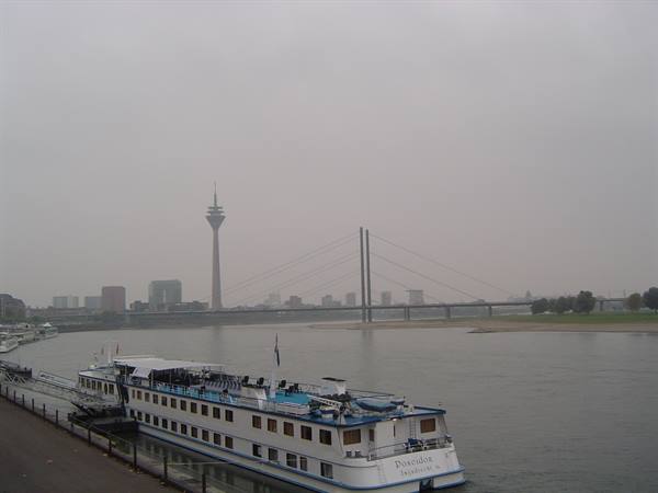 River cruise ship moored on the Rhine, Rheinturm tower and bridge behind