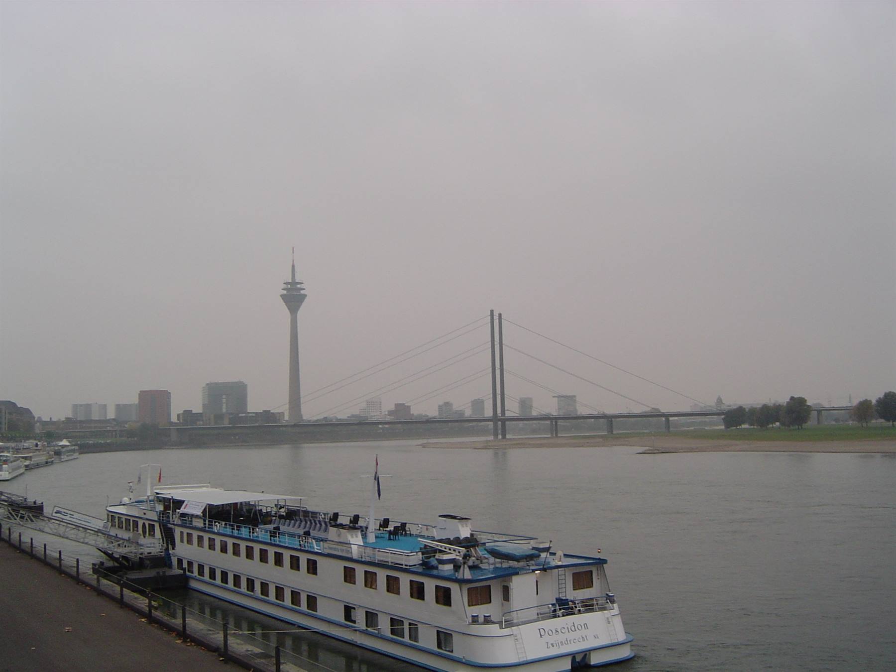 River cruise ship moored on the Rhine, Rheinturm tower and bridge behind