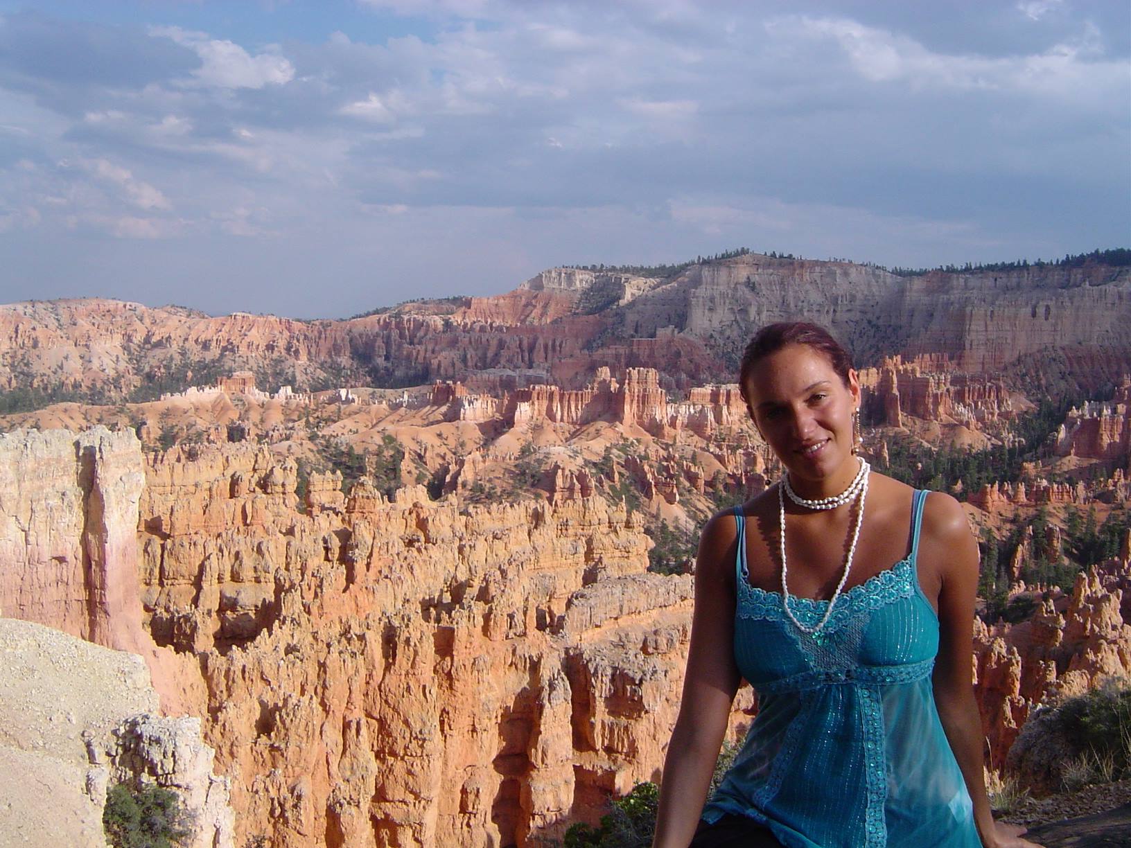 Smiling woman in blue top in front of Bryce Canyon red hoodoos
