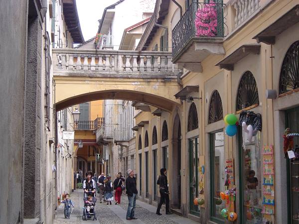 Arcaded street with covered bridge, pedestrians and a toy shop