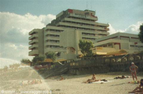 Large concrete hotel above the beach, sunbathers on the sand below