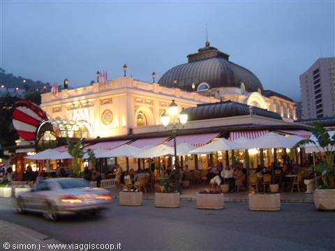 White-awning café terrace beneath the illuminated dome of the Monte Carlo Casino