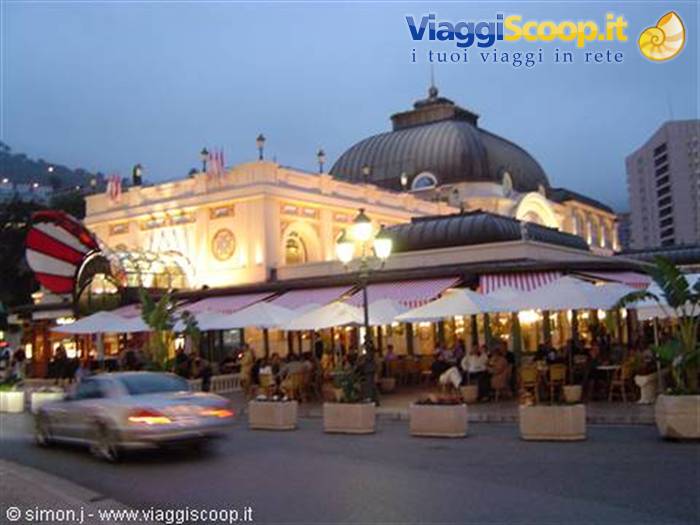 White-awning café terrace beneath the illuminated dome of the Monte Carlo Casino