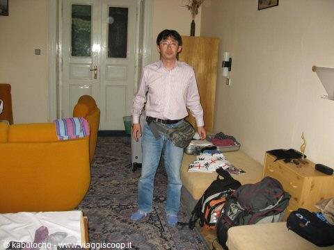 Man in light shirt inside a room with orange sofa and backpacks