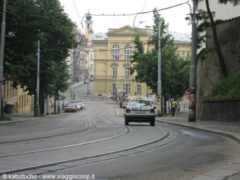 Car approaching on tram tracks street, yellow buildings and trees in Bratislava