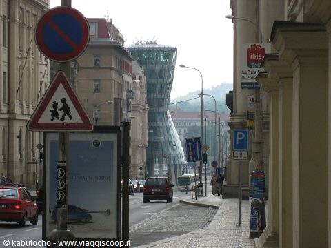 The Dancing House in Prague seen between street signs along the road