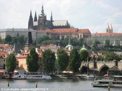 Prague Castle and Charles Bridge over the Vltava, boats moored along the riverbank