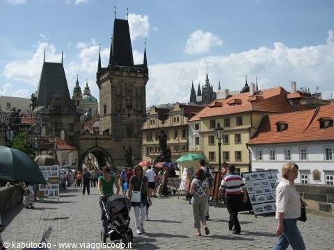 Tourists walking on Charles Bridge, gothic tower and red-roofed houses