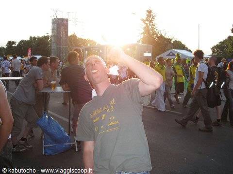 Young man drinking beer at street festival, crowd and lights around