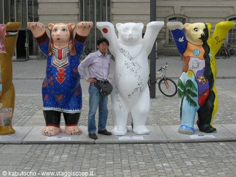 Man posing beside painted Buddy Bears lined up on a square