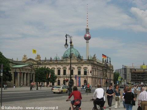 Cyclists and pedestrians on Unter den Linden, historic palace and TV tower in Berlin