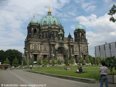 Berlin Cathedral with green stone dome, people relaxing on the lawn