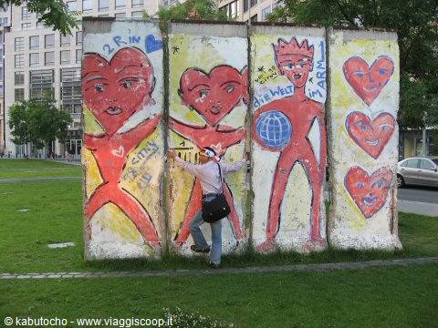 Woman touches painted Berlin Wall segments covered with red hearts