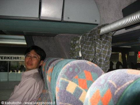 Young man with glasses sitting on a bus, colorful geometric-patterned seats