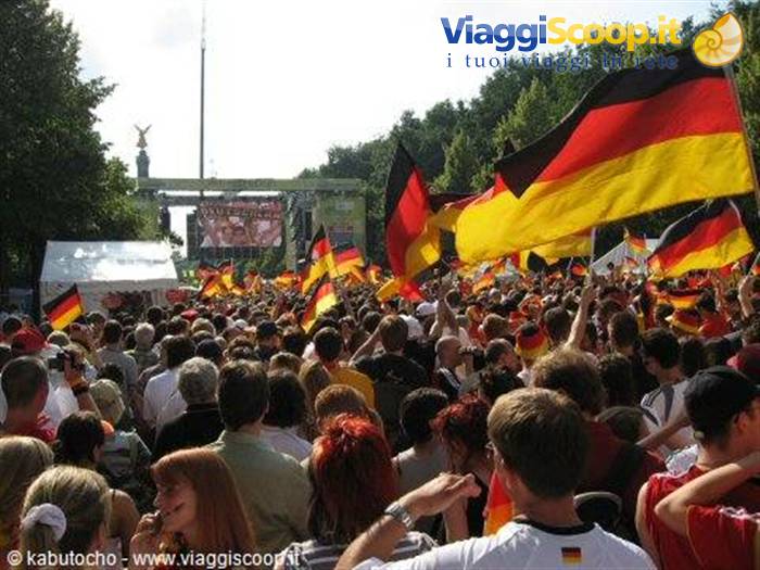 Crowd waving German flags near Berlin's Siegessäule during a public event