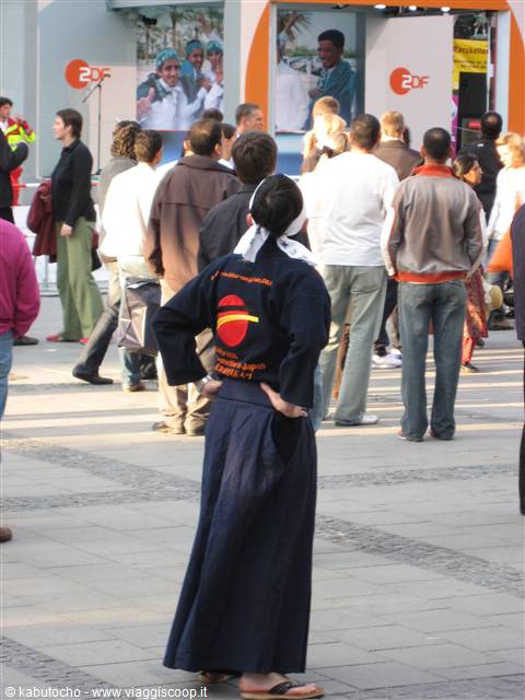 Woman in dark blue kimono with white headband among crowd near ZDF stand