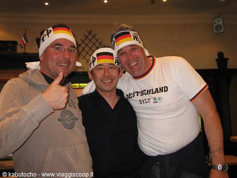 Three German football fans in bandanas smiling inside a warmly lit pub