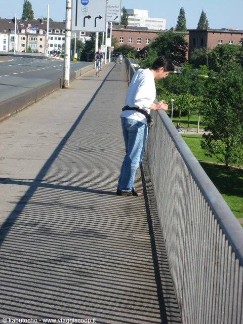 Tourist on a steel bridge leans over the railing in the sun