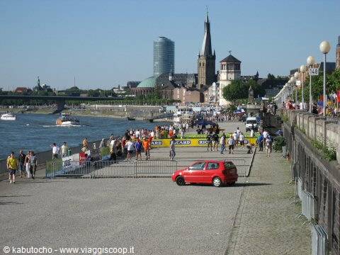 Crowded riverside promenade along the Rhine in Düsseldorf, church tower and skyscraper behind
