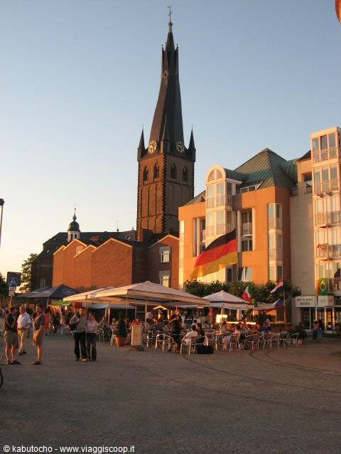 Stone church tower above market stalls and German flag, Düsseldorf