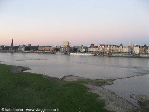 River with grassy bank and colorful townhouses along the waterfront, evening light