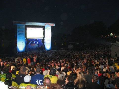 Night crowd watching a giant illuminated screen at Circo Massimo, packed stands