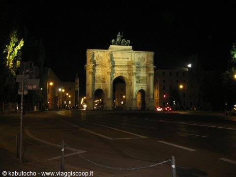 Illuminated triumphal arch at night, stone quadriga above the arches