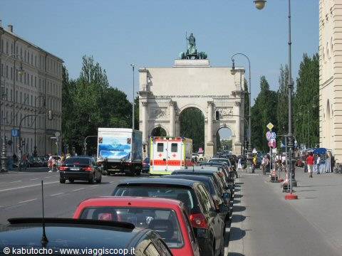 Parked cars and traffic in front of Munich's Siegestor, stone arch with bronze statue