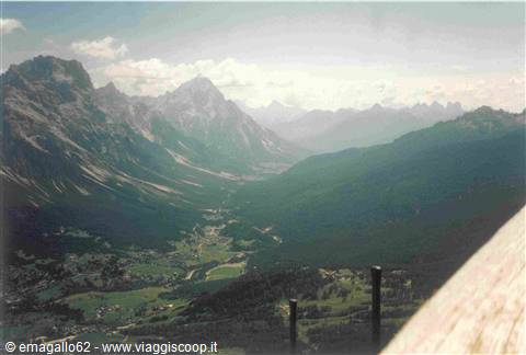 Green valley with a village among the rocky Dolomite peaks