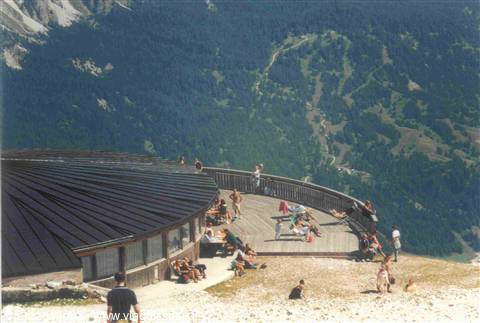 Tourists rest on the wooden terrace of a round mountain refuge in the Dolomites