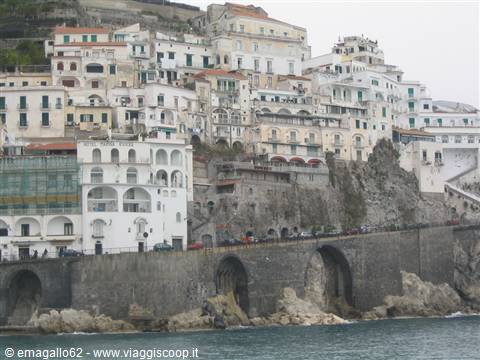 White houses stacked on the cliff above stone arches, Amalfi