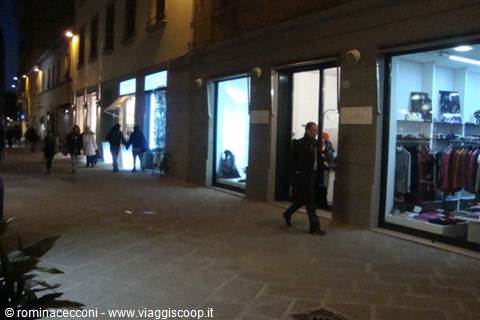 People walking past illuminated shop windows on an evening street