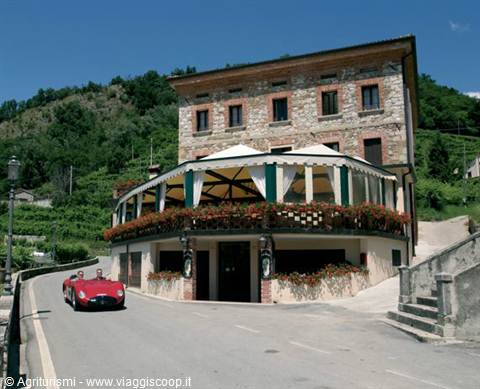Vintage red sports car outside a stone restaurant among hillside vineyards