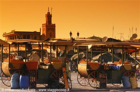 Orange carts on Jemaa el-Fna square, Marrakech, minaret against amber light
