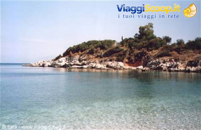 clear turquoise water in front of white rocks and green hillside