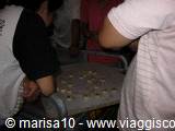 People seated at a table work on small light objects in a dark room