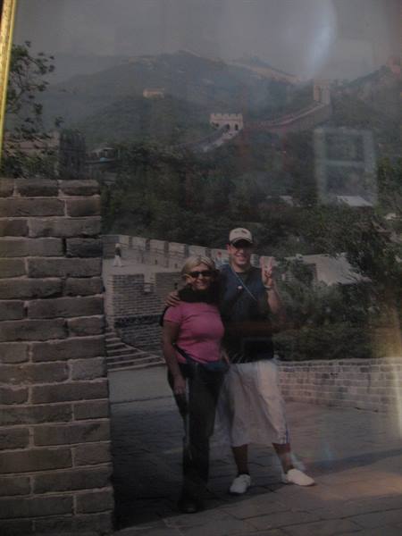 Two tourists posing on the Great Wall, stone walls and hazy mountains behind