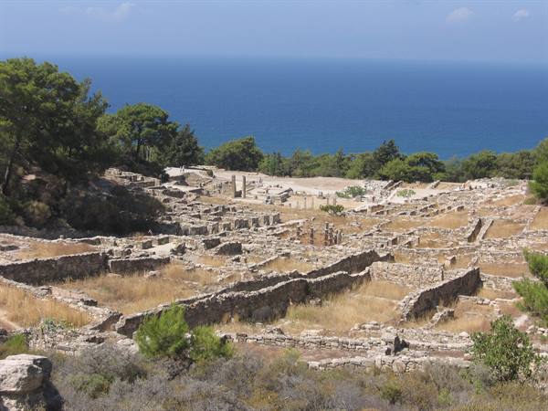 Stone ruins of ancient Kamiros among pine trees, Aegean Sea in the background
