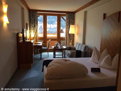 Wooden hotel room with bed, striped sofa and windows overlooking snowy mountains