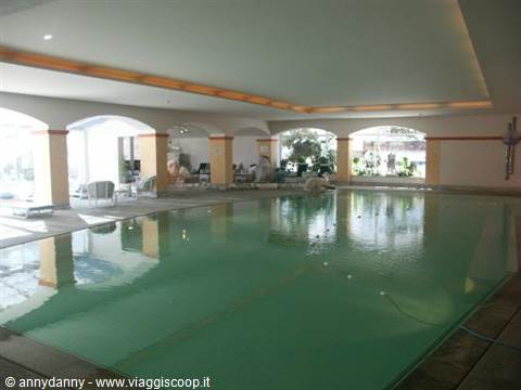 Indoor green-water pool with white arches and natural light from windows