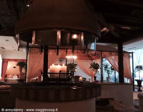 Round masonry fireplace with lit candles, pink drapes and torches among plants