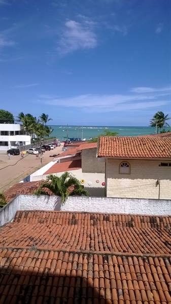 Red tiled rooftops in front of turquoise sea with palm trees and white houses