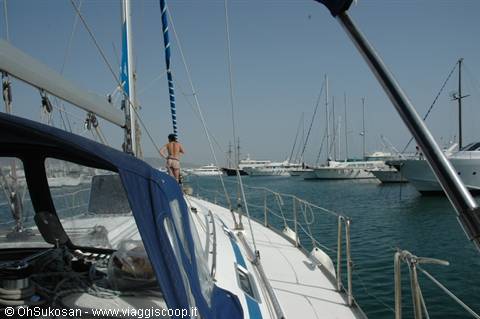Woman in bikini on a sailboat deck among yachts in the marina