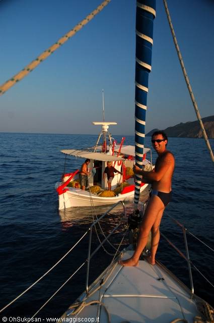 Man in the sea grabs the pole near a Greek fishing boat