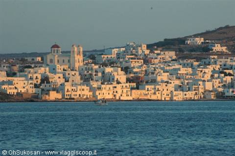Whitewashed village by the sea with church and bell tower, small boat nearby