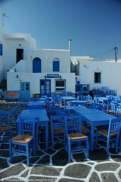Blue tables and chairs on a whitewashed Cycladic square