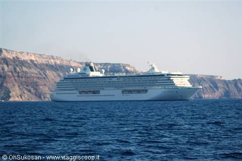 White cruise ship anchored in front of Santorini cliffs